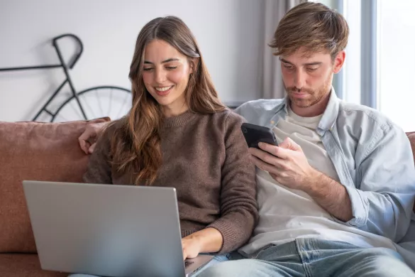 Man en vrouw bekijken website op laptop en smartphone